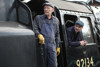 Locomotive footplate staff look out from the cab of a steam locomotive.