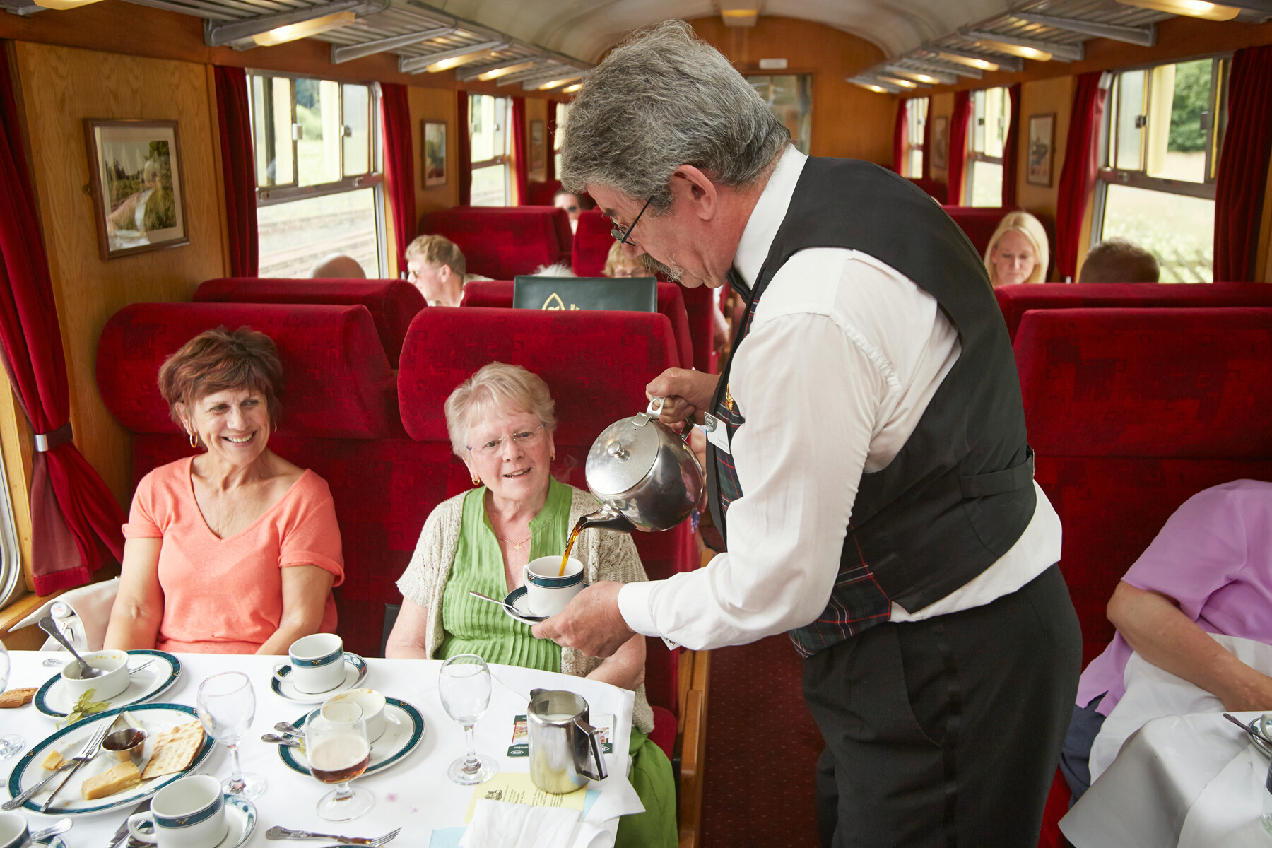 A Pullman Steward pours a fresh cup of tea for a North Yorkshire Pullman Dining passenger.