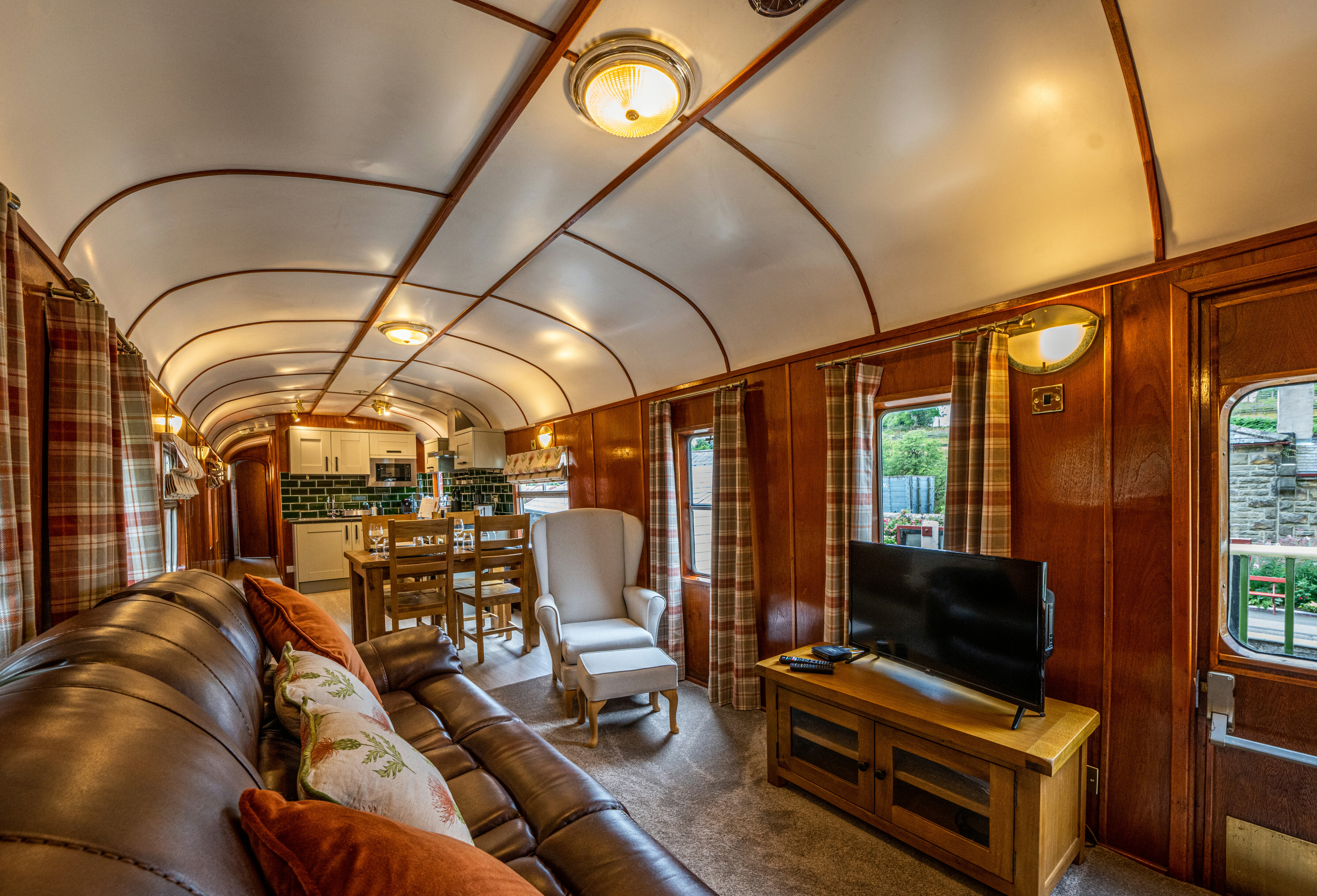 Goathland Camping Coach living room with settee, comfy chair and flat-screen television visible.