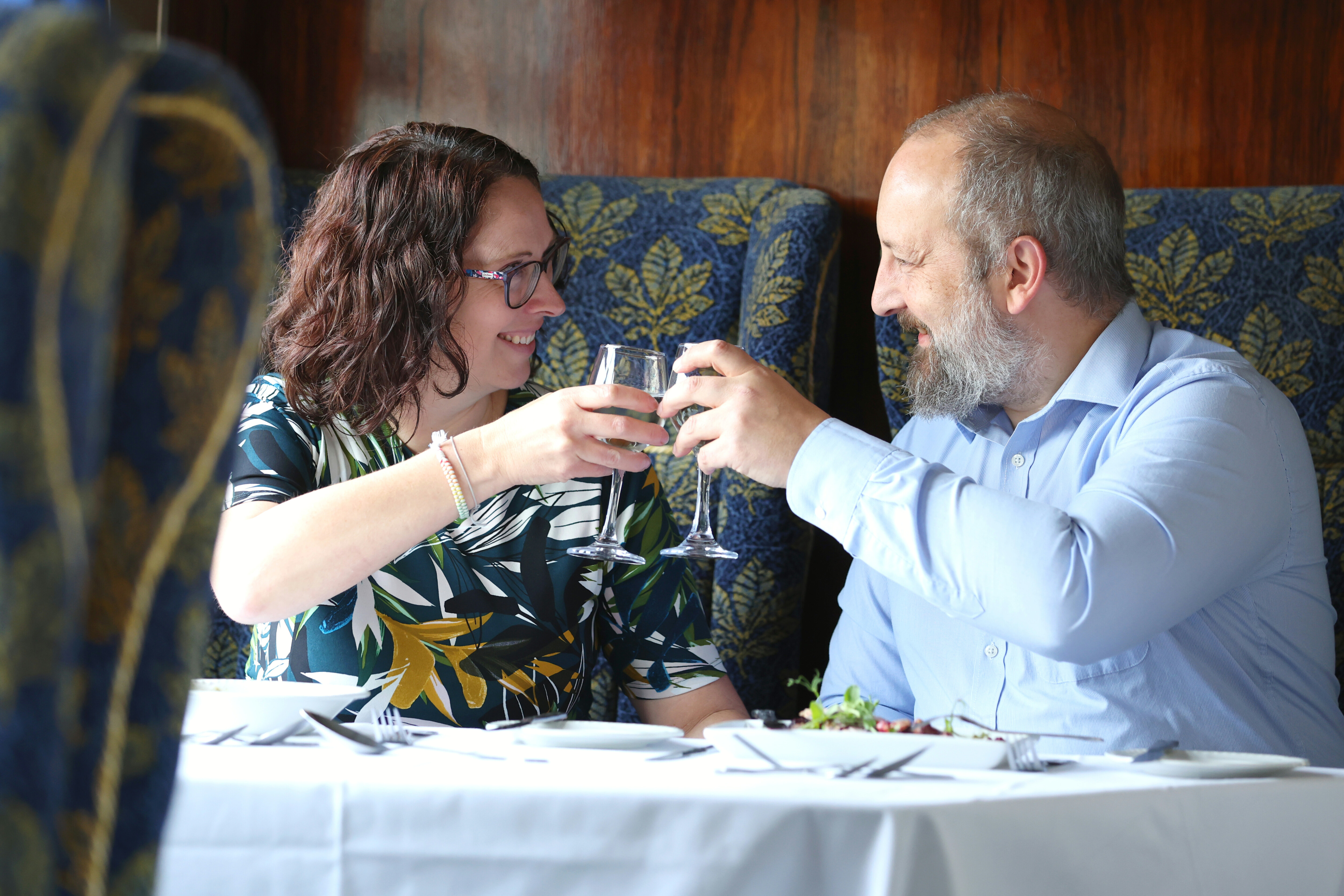 A couple on the North Yorkshire Pullman celebrate by raising wine glasses to one another.