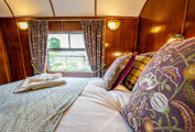 Goathland Camping Coach double bedroom, with flowery cushions and views on to the station.