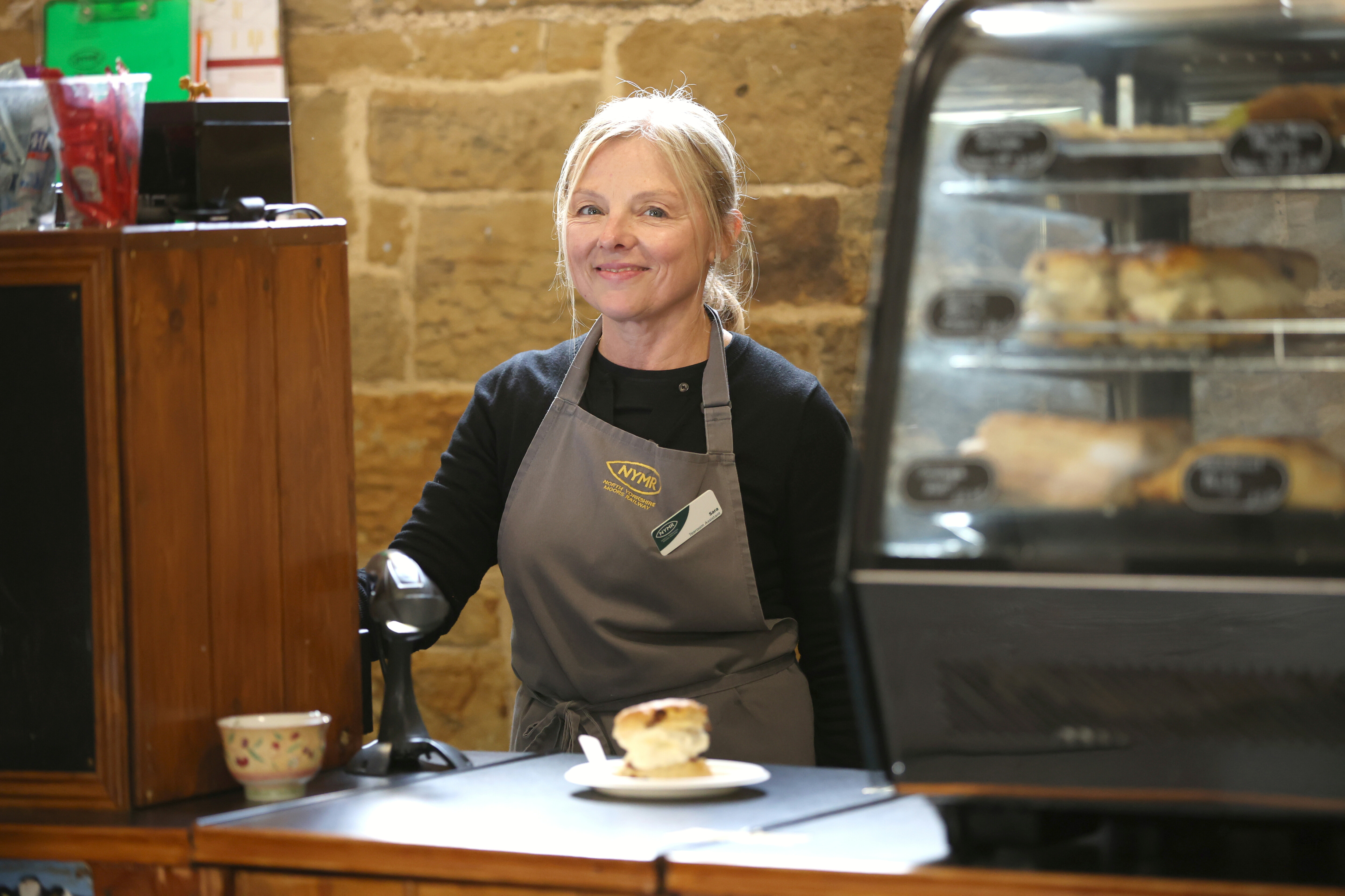 A tearoom assistant behind the counter at Goathland Warehouse Tearoom.