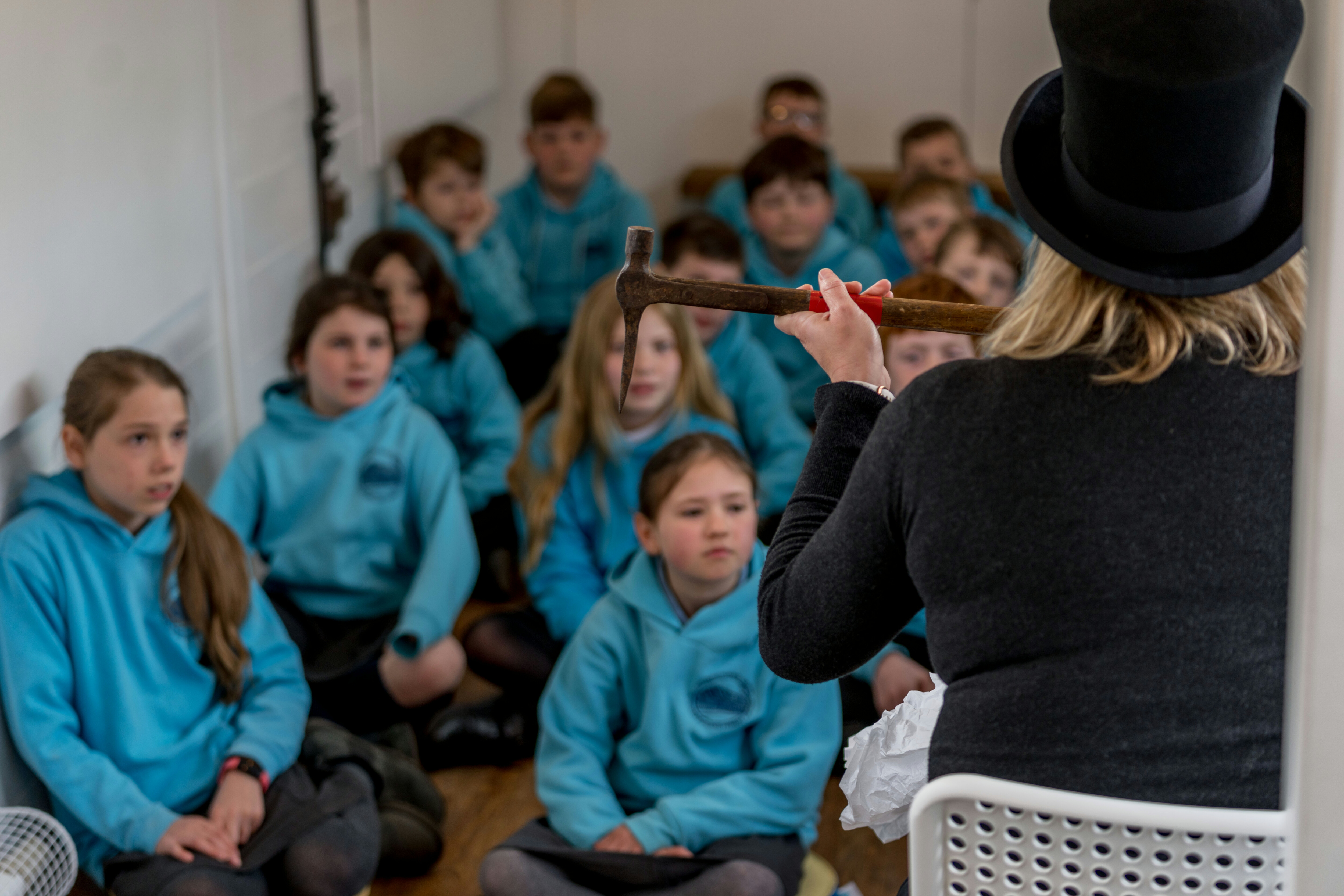 An educator shows children a piece of historic work tools.