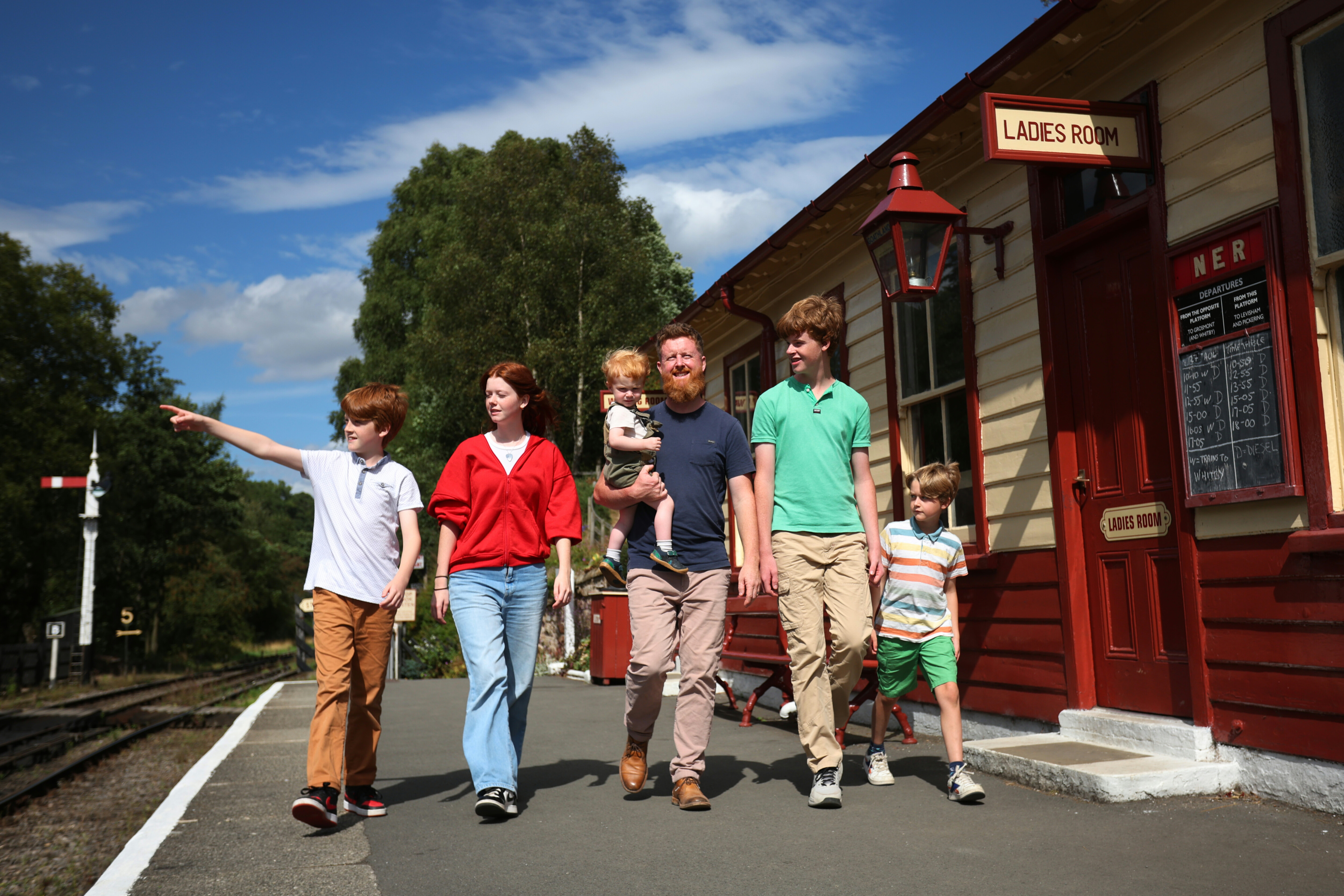A family walk along Goathland Station platform in the summer sun.