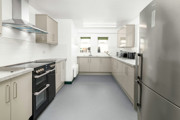 The kitchen at The Outstation which has beige cupboards, a grey floor and white walls.