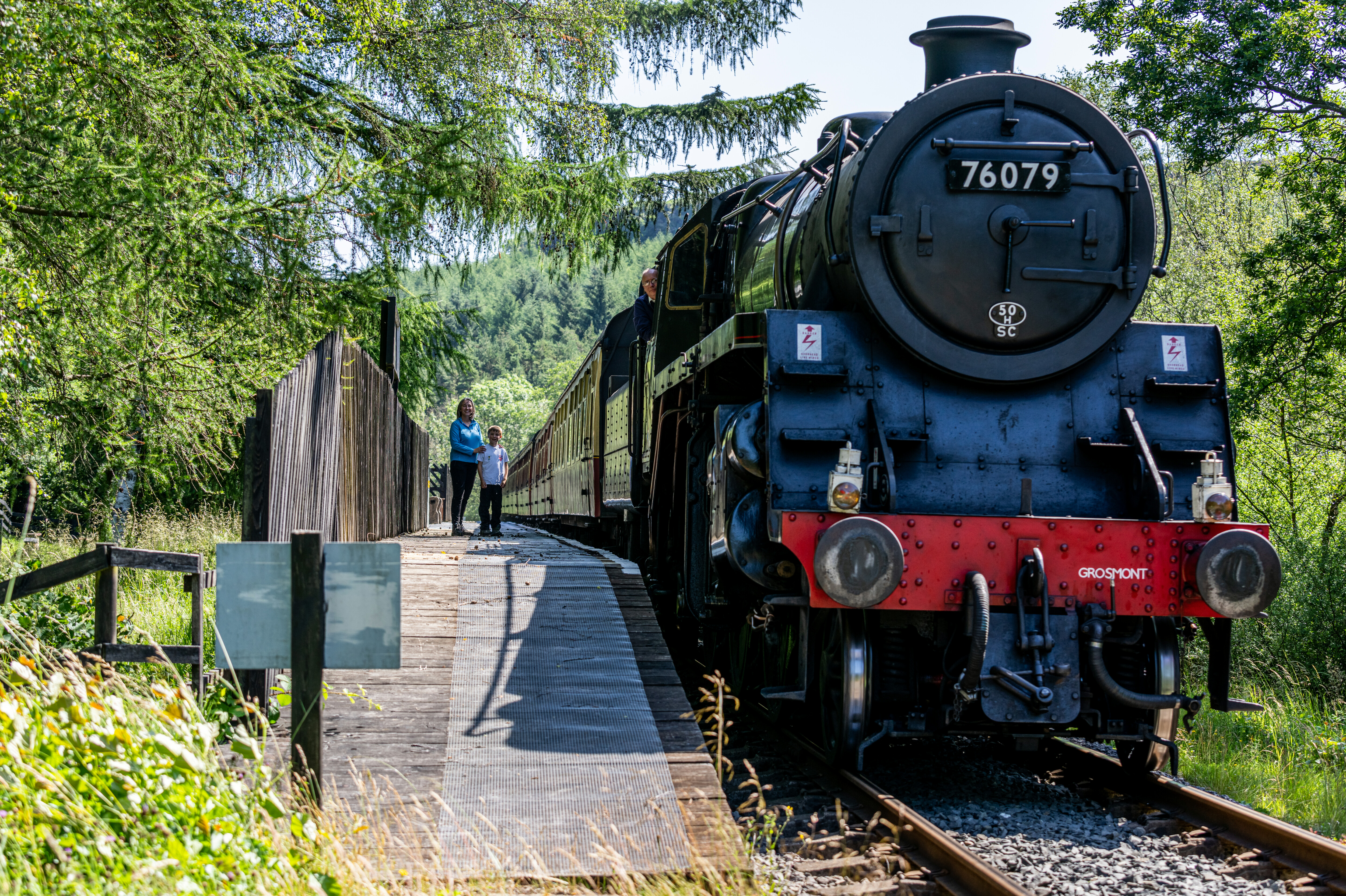 Mother and son look out from Newtondale platform with No. 76079 on the railway line.