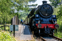 Mother and son look out from Newtondale platform with No. 76079 on the railway line.
