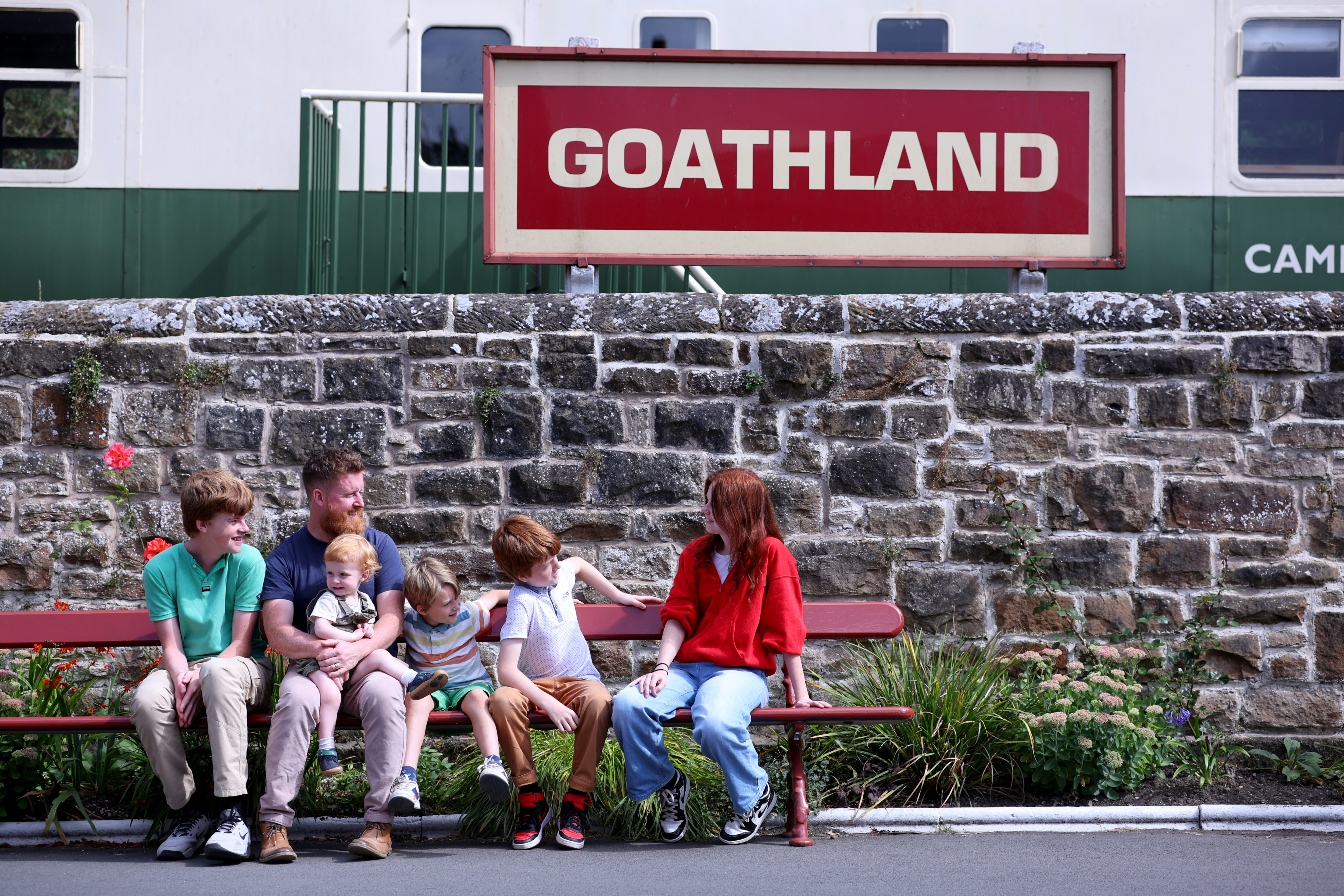 A family sit on a bench at Goathland Station.