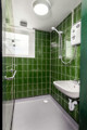 The Outstation wet room with green tiles on the walls and white fittings.
