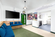 A room at The Outstation with blue upholstered wooden bench seats looking into the open plan kitchen.