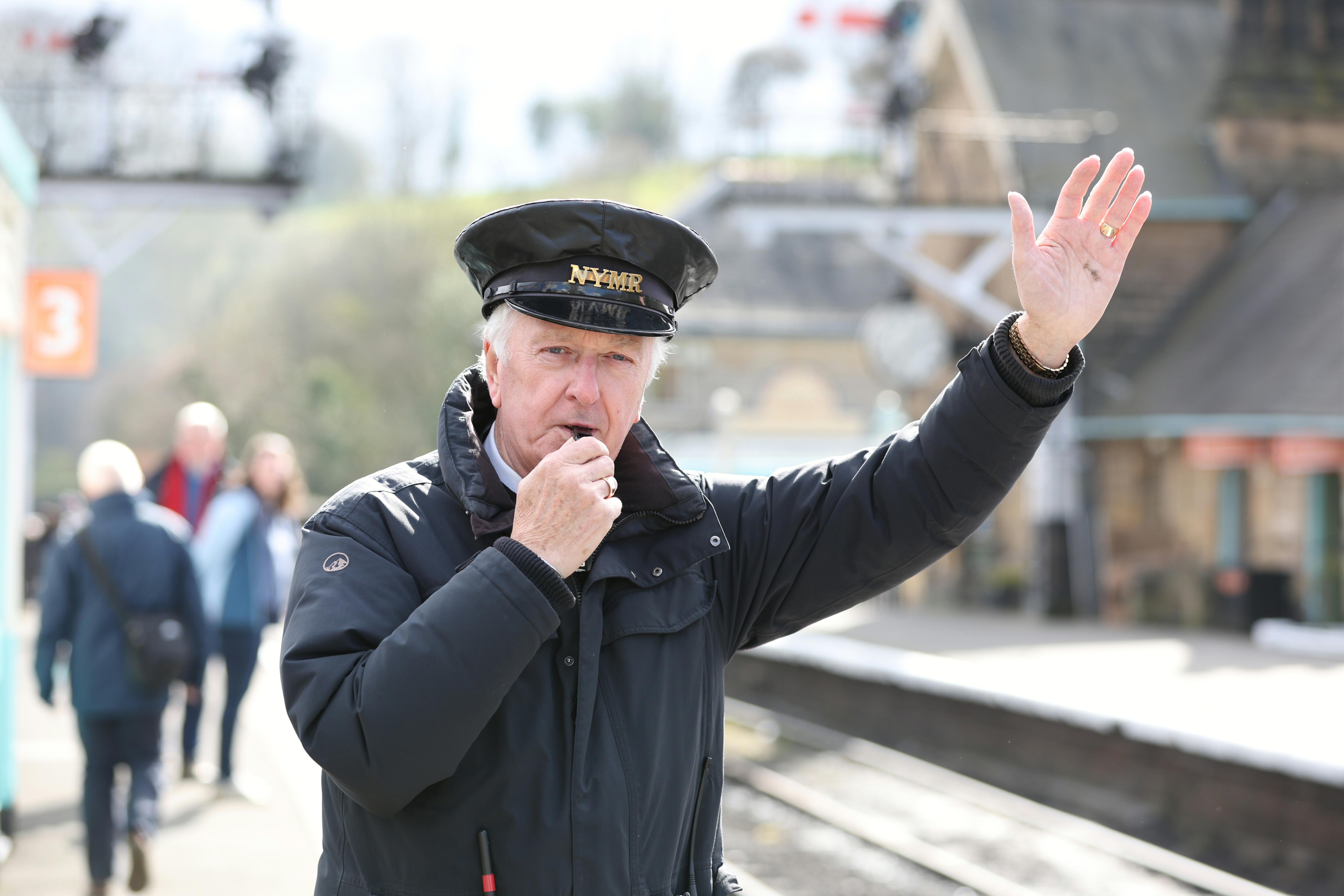 A member of Station Staff blow their whistle at Grosmont Station.
