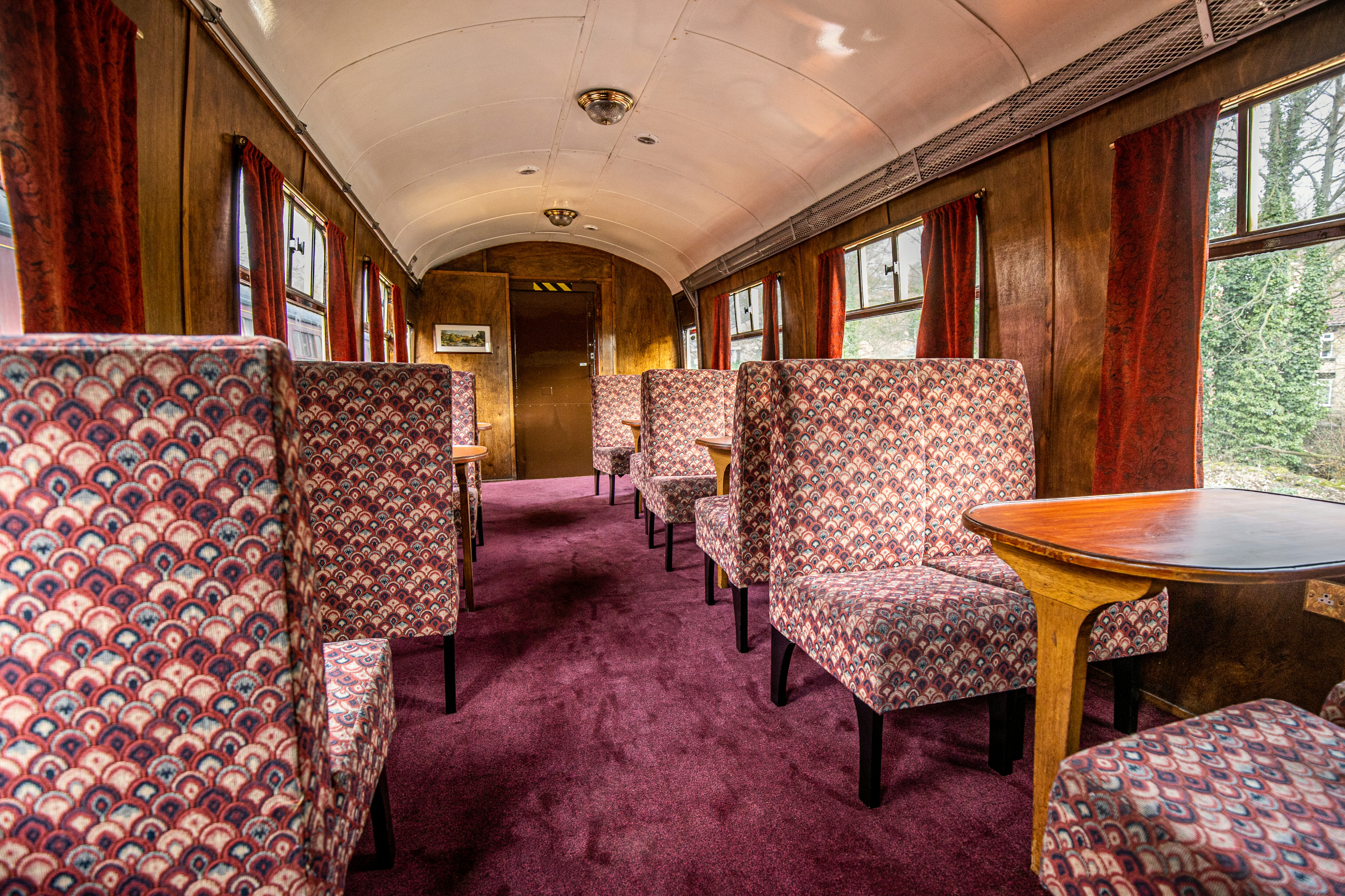 A carriage for disabled people with extra space and movable chairs all beautifully furnished in plum colours.