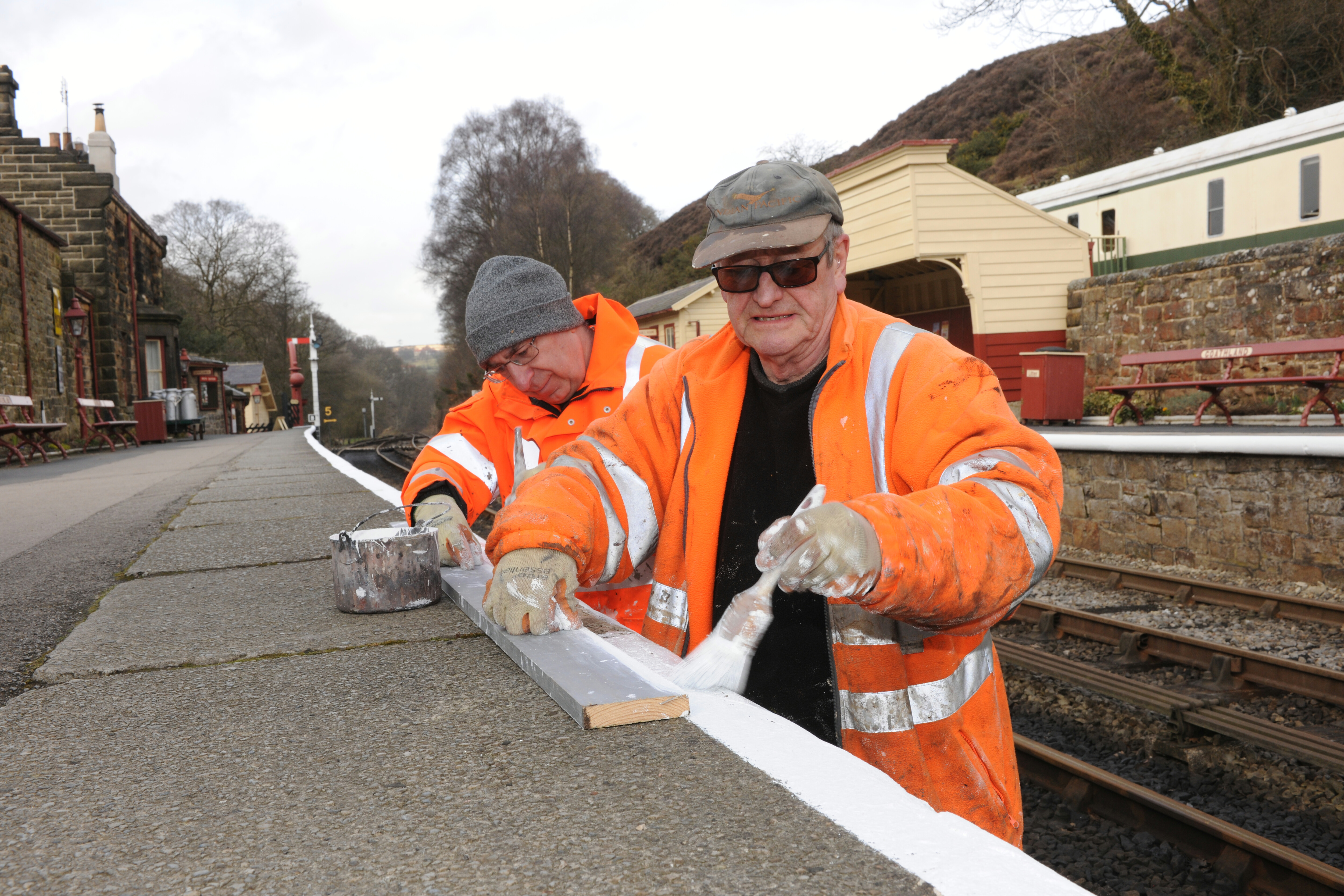 Two volunteers help to paint the white lines on the platform at Goathland Station.